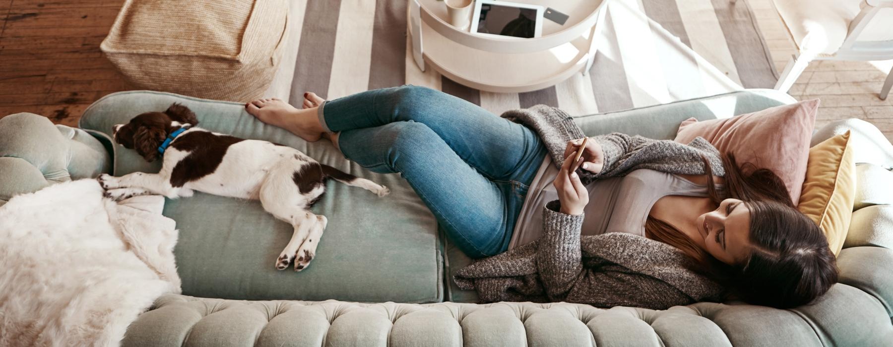 a person lying on a couch with a dog