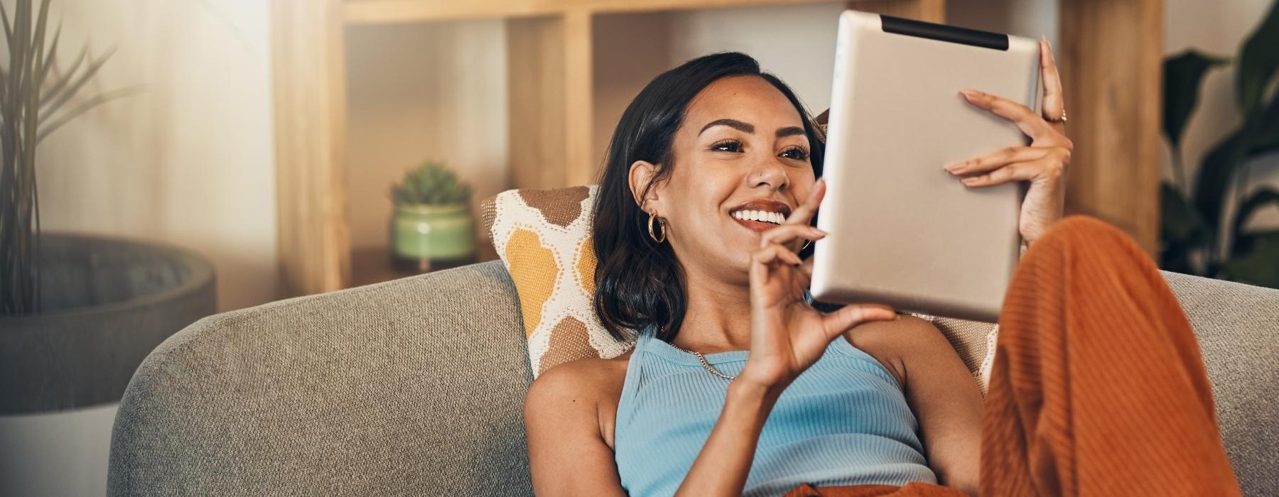 a person sitting on a couch holding a tablet